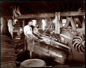 Interior view of two men working with leather and heavy equipment at the New York Leather Belting Co., New York, 1905